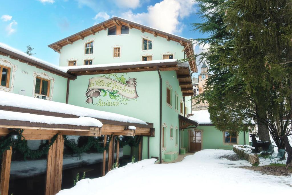 un edificio con un cartel en la nieve en La Valle del Gran Sasso, en Assergi