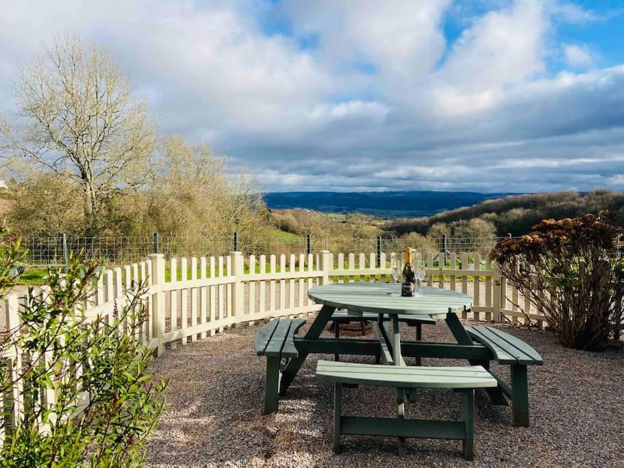 a picnic table in front of a white fence at The Chaff House Country Cottage in Welsh Newton Common