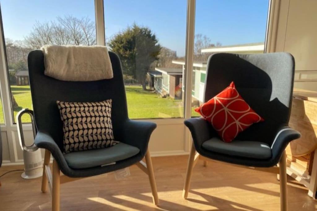 two chairs sitting next to each other in front of a window at The View. Stylish modern Chalet in great location. in Cromer