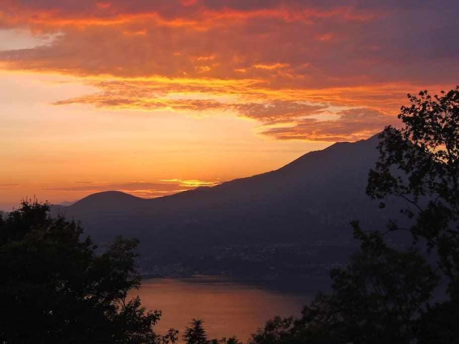 una puesta de sol sobre un cuerpo de agua con una montaña en La Terrazza Baldo Garda, en San Zeno di Montagna