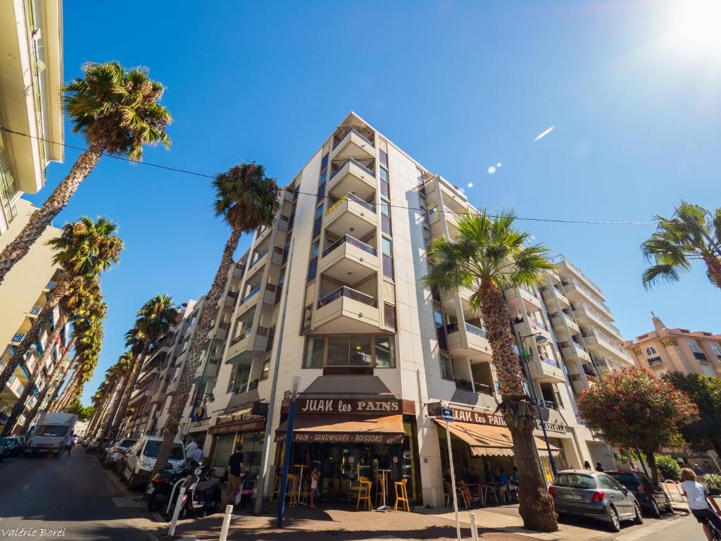 un grand bâtiment avec des palmiers devant dans l'établissement Résidence Graziella Studio 309, à Juan-les-Pins