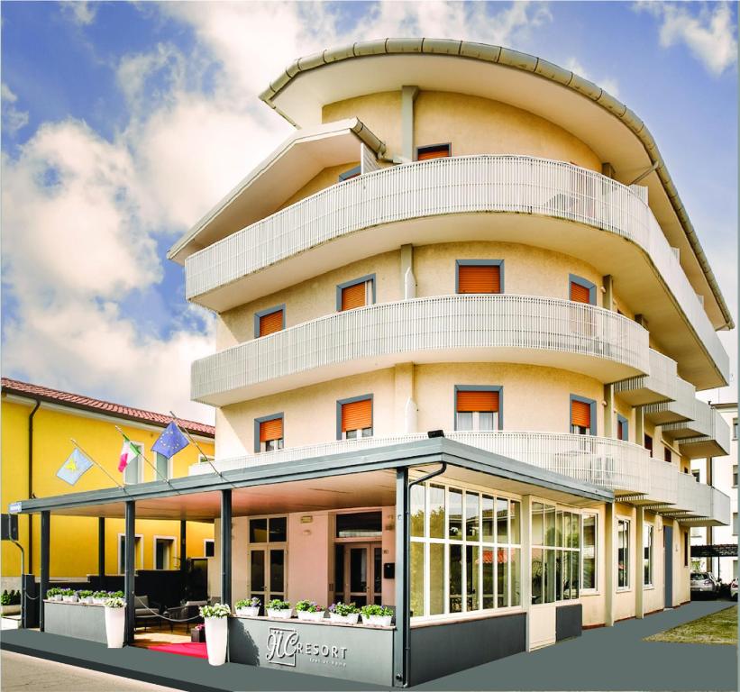 un gran edificio amarillo con una parte superior redonda en Hotel Hc Resort Lignano en Lignano Sabbiadoro