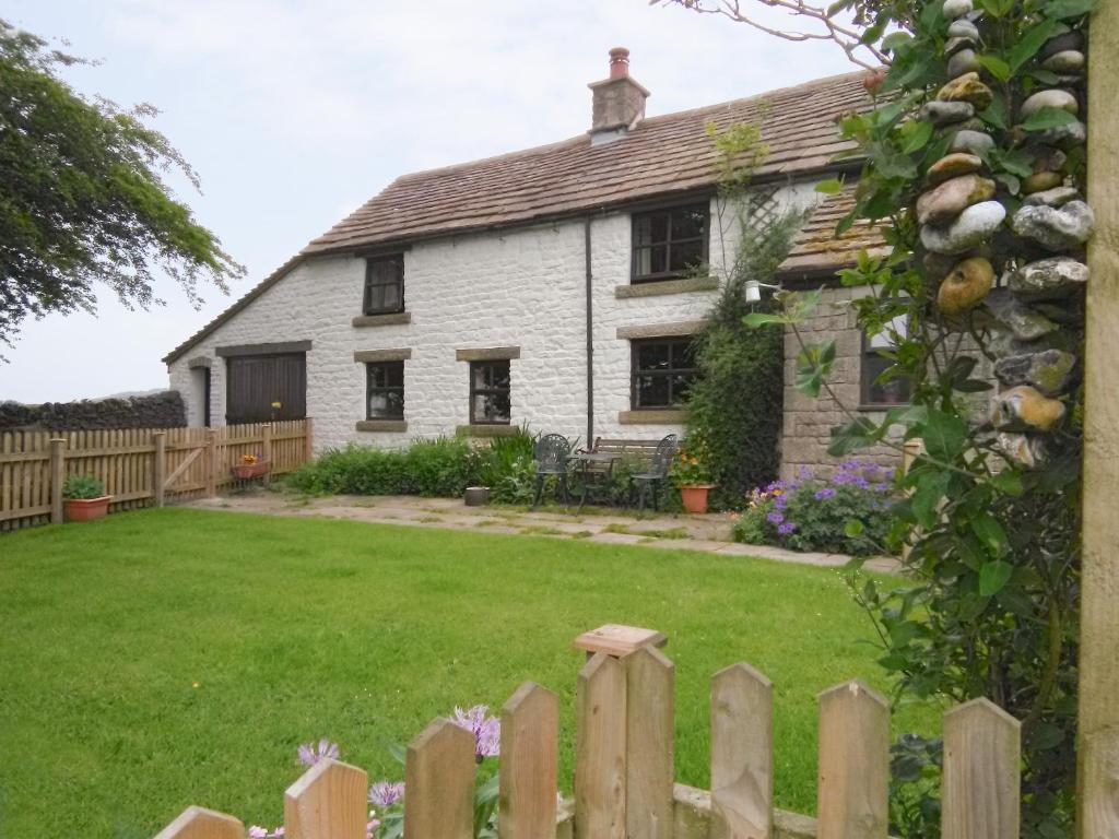 ein weißes Haus mit einem Zaun und einem Hof in der Unterkunft Oxlow End Cottage in Peak Forest