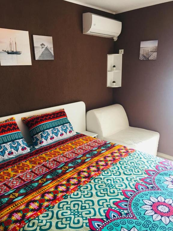a bed with a colorful blanket and a chair in a room at Garsonierele Alexandru in Saturn