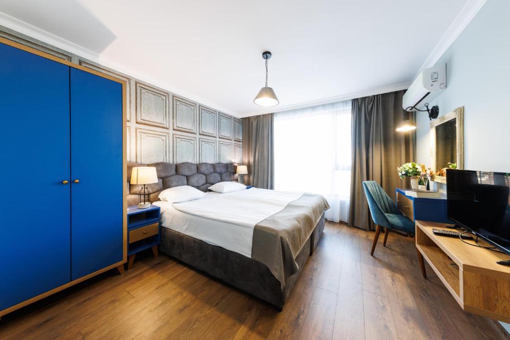 een slaapkamer met een bed, een bureau en een televisie bij Avenue Hotel - Free Parking in Sofia