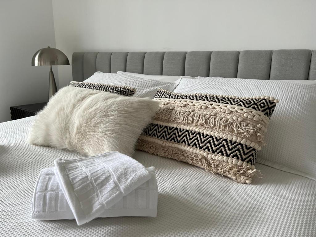 a bed with white pillows and a gray head board at URALLA STUDIO - South Coast - Private Guest Suite in Bomaderry