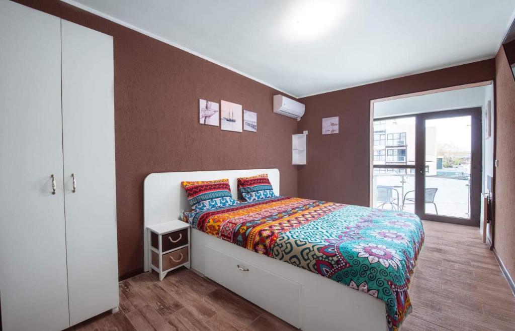 a bedroom with a bed with a colorful comforter at Garsonierele Alexandru in Saturn