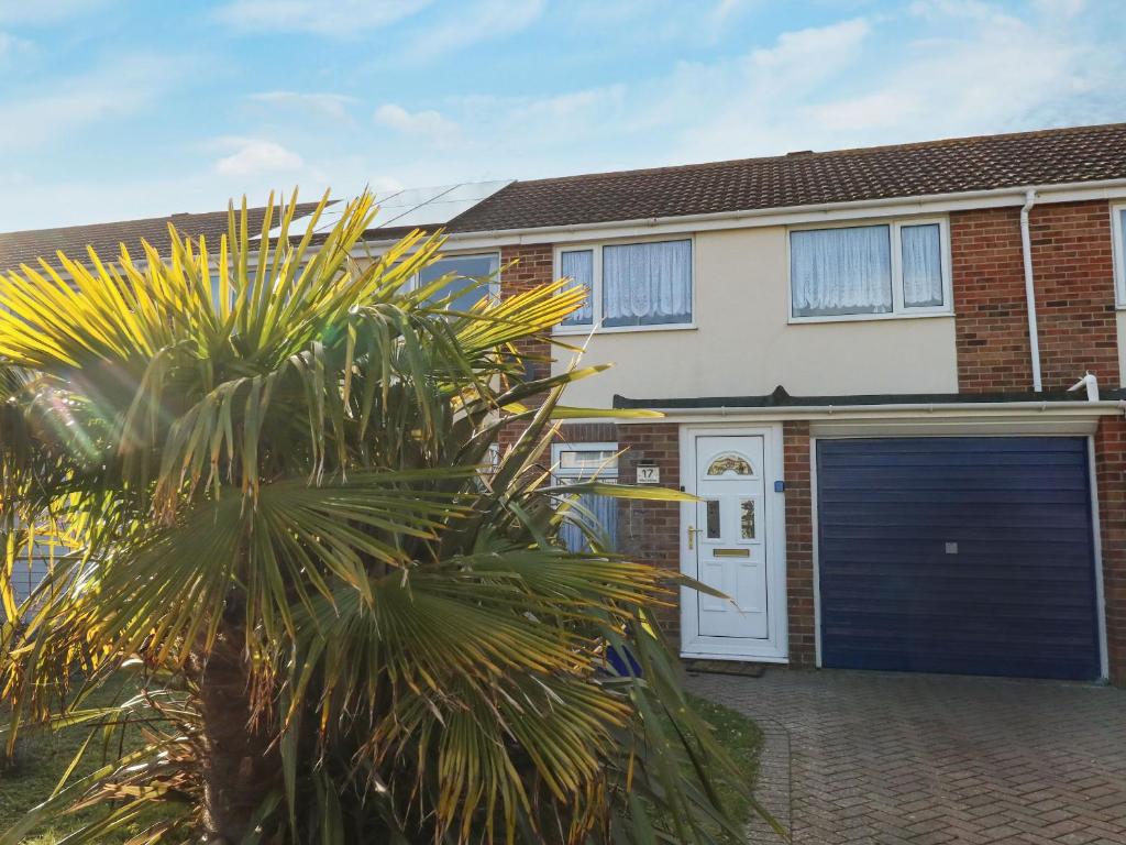 a house with a blue garage door and a palm tree at Milton House in Weymouth