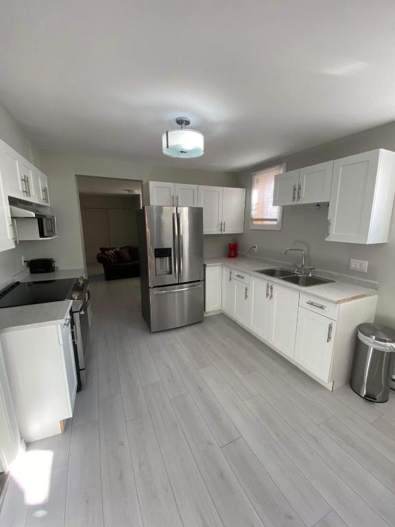 a kitchen with white cabinets and a stainless steel refrigerator at Le Cardinal in Rouyn