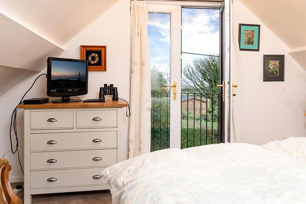 Dormitorio con cama y tocador con TV en Bodfryn Cottage, en Llangoed