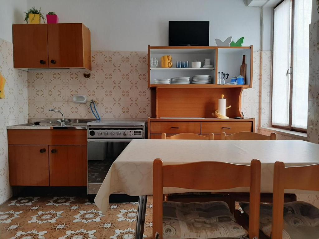 cocina con mesa, fregadero y fogones en Casa dei Tulipani Tenna Ospitar en Tenna 
