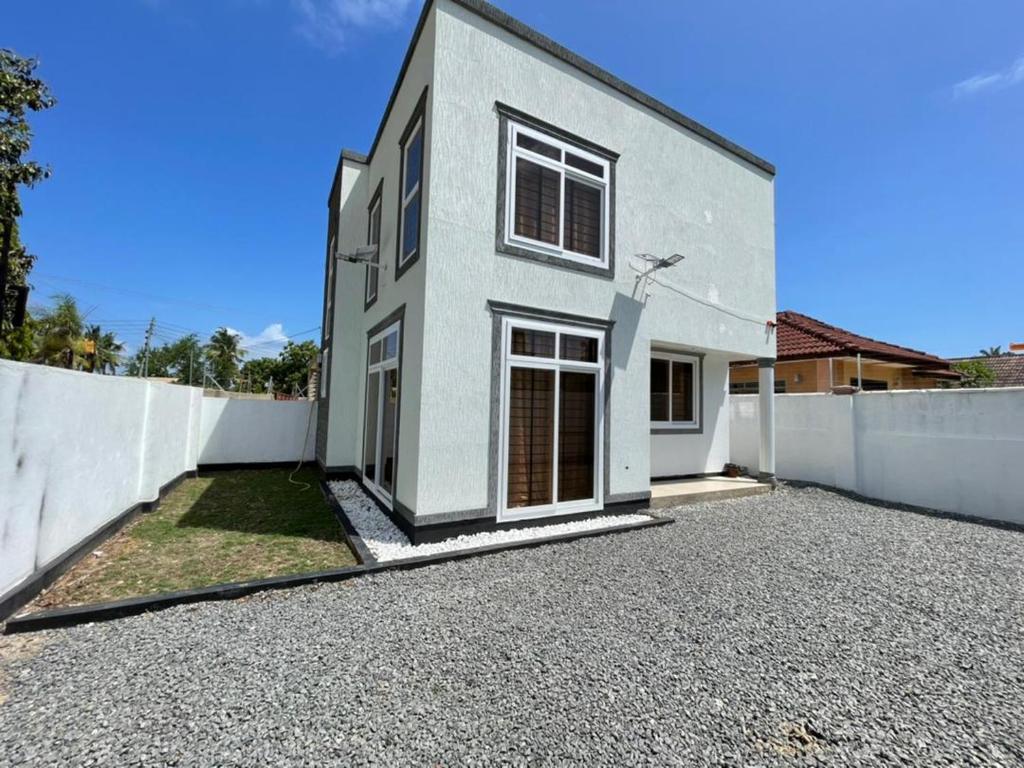 uma casa branca com uma cerca e uma entrada em Travellers stay em Dar es Salaam