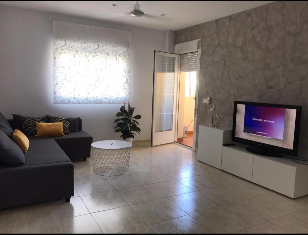 a living room with a couch and a flat screen tv at Piso luminoso cerca de la playa in Roquetas de Mar