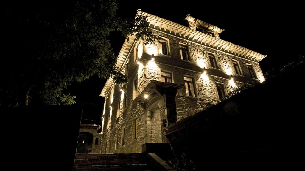 a large stone building with lights on it at night at VILLA PERMET in Përmet