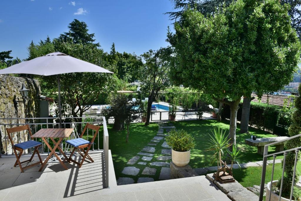 um pátio com um guarda-sol, uma mesa e cadeiras em Douro Mool Guest House em Lamego