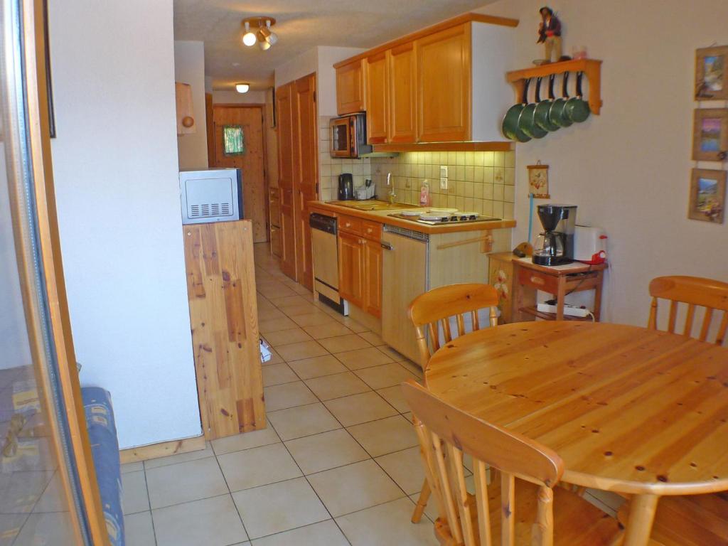 une cuisine avec une table en bois et une salle à manger dans l'établissement Appartement cosy avec balcon, parking et animaux acceptés - FR-1-629-90, à Morillon