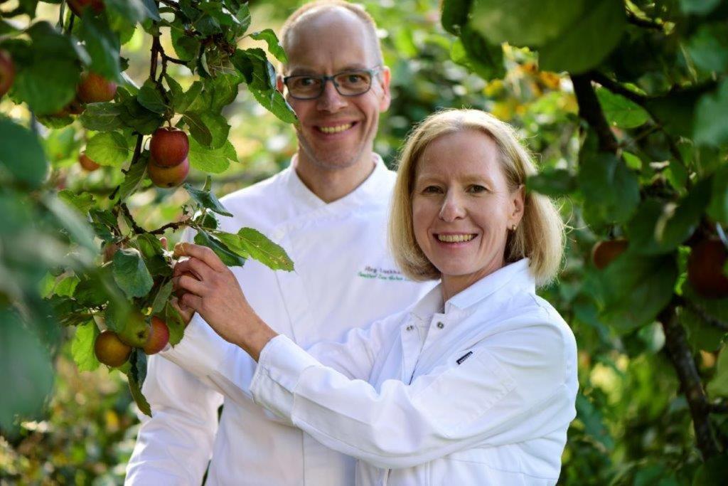 a man and a woman standing next to an apple tree at Gasthof Zum Hohen Lohr in Battenhausen