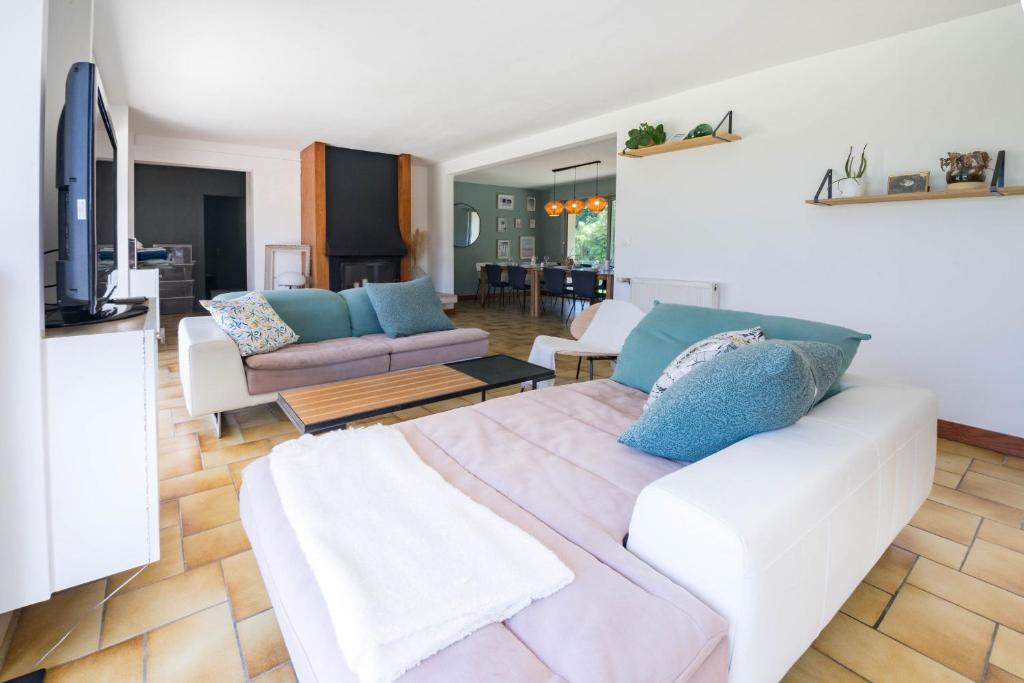 ein Wohnzimmer mit einem weißen Sofa und einem TV in der Unterkunft TY AR MENEZ - Grande maison familiale proche plage in Landunvez