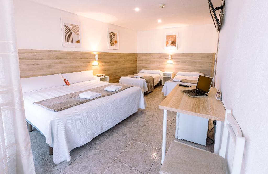 a room with three beds and a laptop on a table at Hostal Gran Vía in Pinto