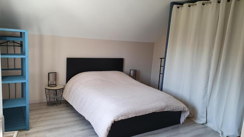 ein Schlafzimmer mit einem Bett mit einer weißen Tagesdecke in der Unterkunft Studio au centre du triangle Reims-Epernay-Chalons 