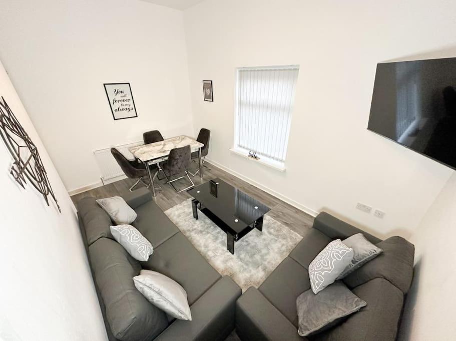 ein Wohnzimmer mit einem Sofa und einem Tisch in der Unterkunft Spacious Five Bed Home in Liverpool