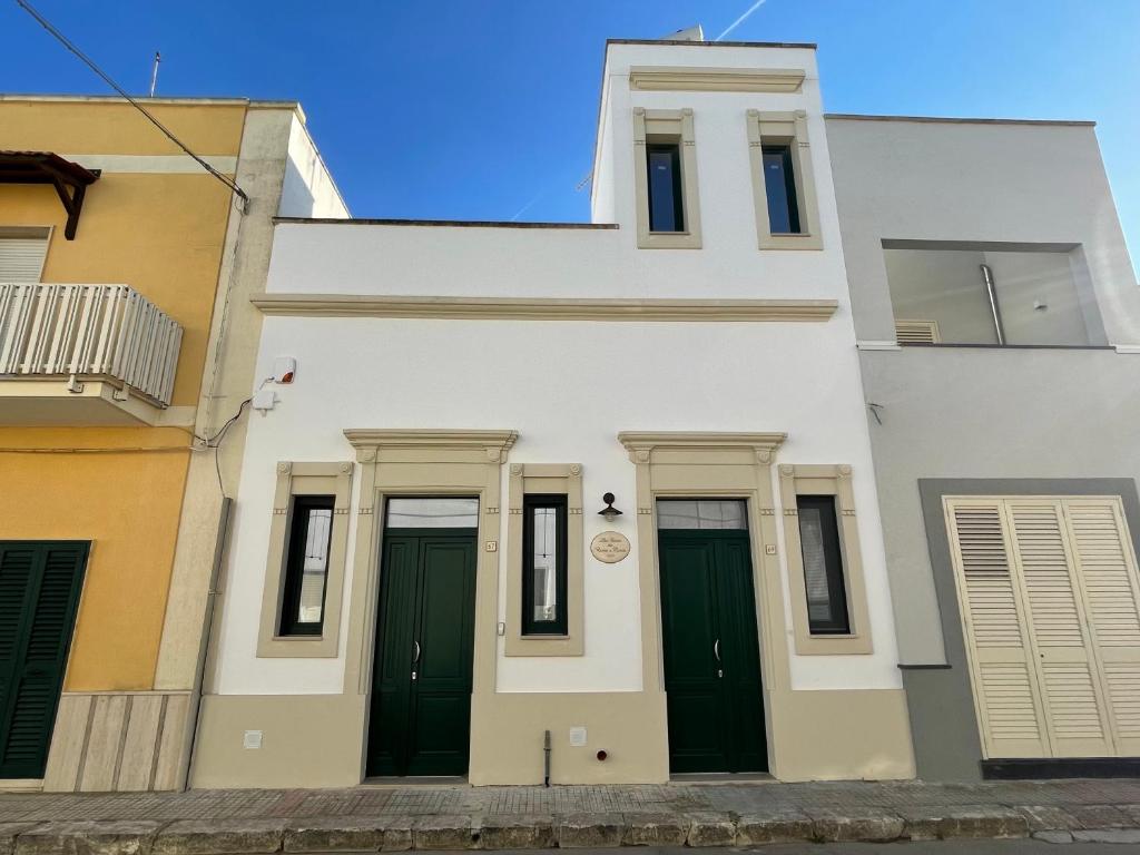 un edificio blanco con puertas verdes en una calle en La Casa di Rocco e Maria 1947, en Porto Cesareo