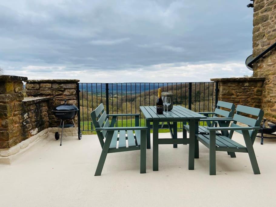 a picnic table and chairs on a patio with a grill at The Cider House Holiday Cottage in Welsh Newton Common