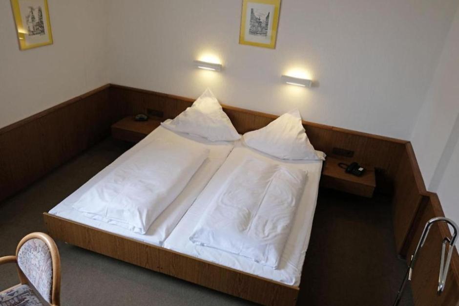 una camera da letto con letto, lenzuola e cuscini bianchi di Lessinghof a Braunschweig