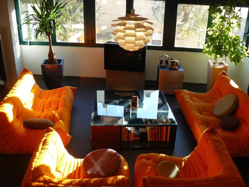 una sala de estar con 2 sofás naranjas y una mesa. en LOFT A RODA DE BERÀ, en Roda de Bará