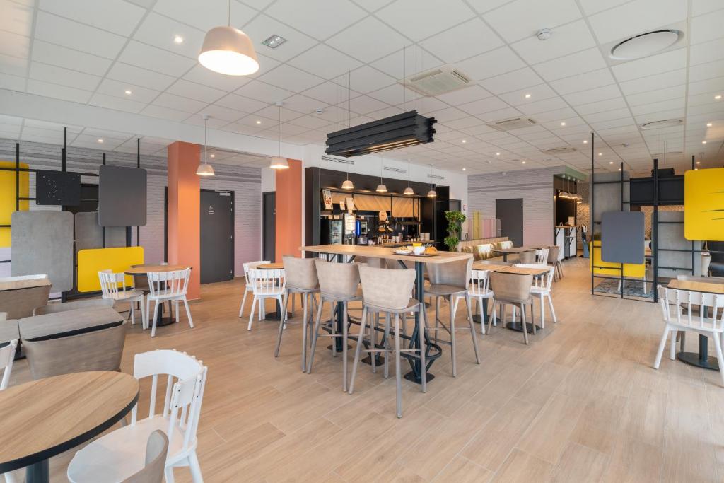 um restaurante com cadeiras e mesas brancas e um bar em B&B HOTELS Bourg-en-Bresse Viriat em Viriat