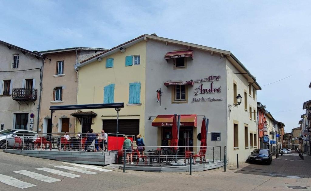 un edificio con gente sentada fuera de él en una calle en LA FERME D'ANDRE, 