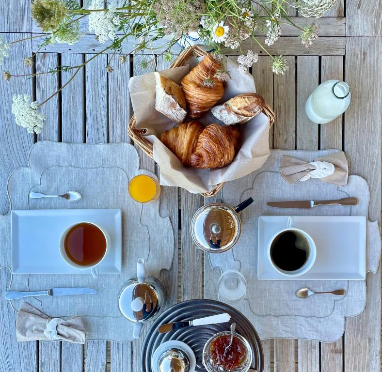 einen Tisch mit einem Korb Brot und Tassen Kaffee in der Unterkunft Villa Amahe - Chambres d'hôtes au coeur de Piriac sur Mer in Piriac-sur-Mer
