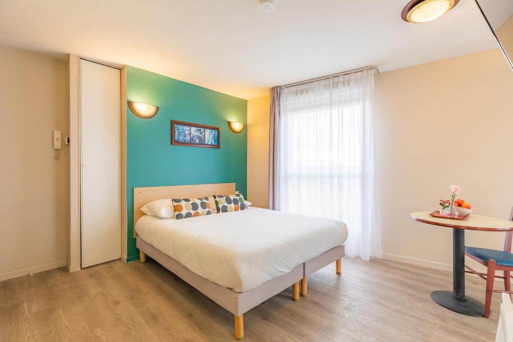 - une chambre avec un lit et un mur vert dans l'établissement Appart'City Classic Lyon Villeurbanne, à Villeurbanne