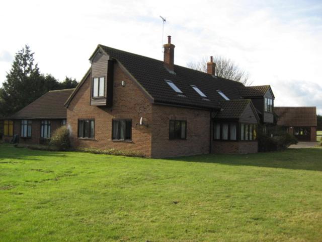een groot bakstenen huis met een groene tuin ervoor bij Clare House in Mundford