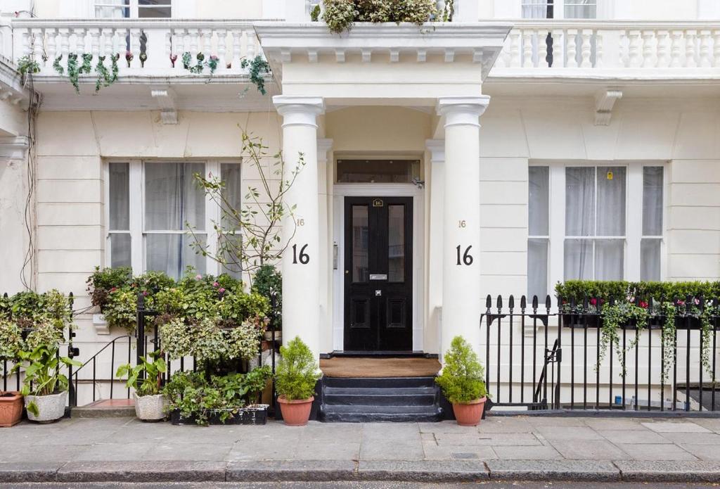 uma casa branca com uma porta preta e vasos de plantas em Litsa's Central Studios em Londres