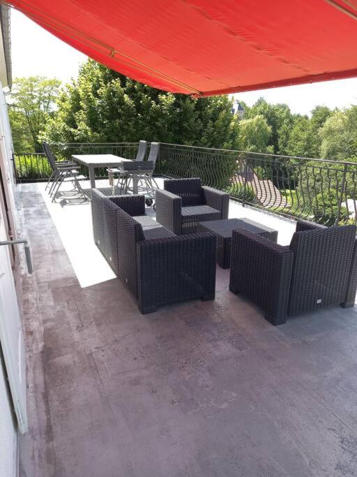 a patio with tables and chairs and a red umbrella at La Grimpette in Châtillon-en-Bazois