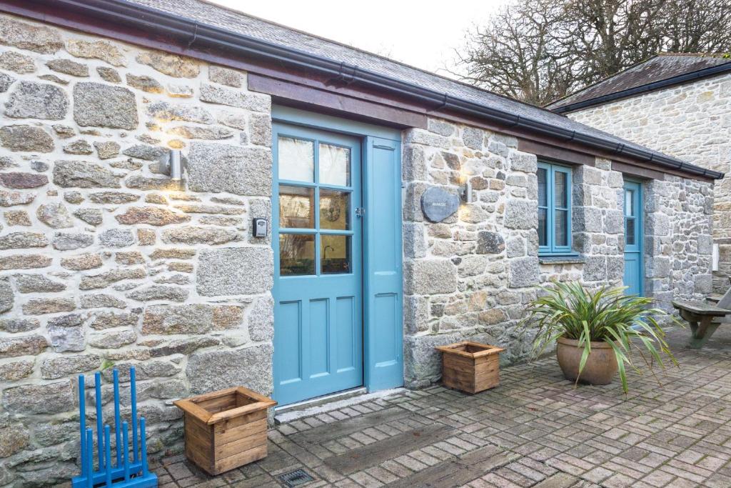 a stone house with a blue door and a patio at Manacles in Mawnan