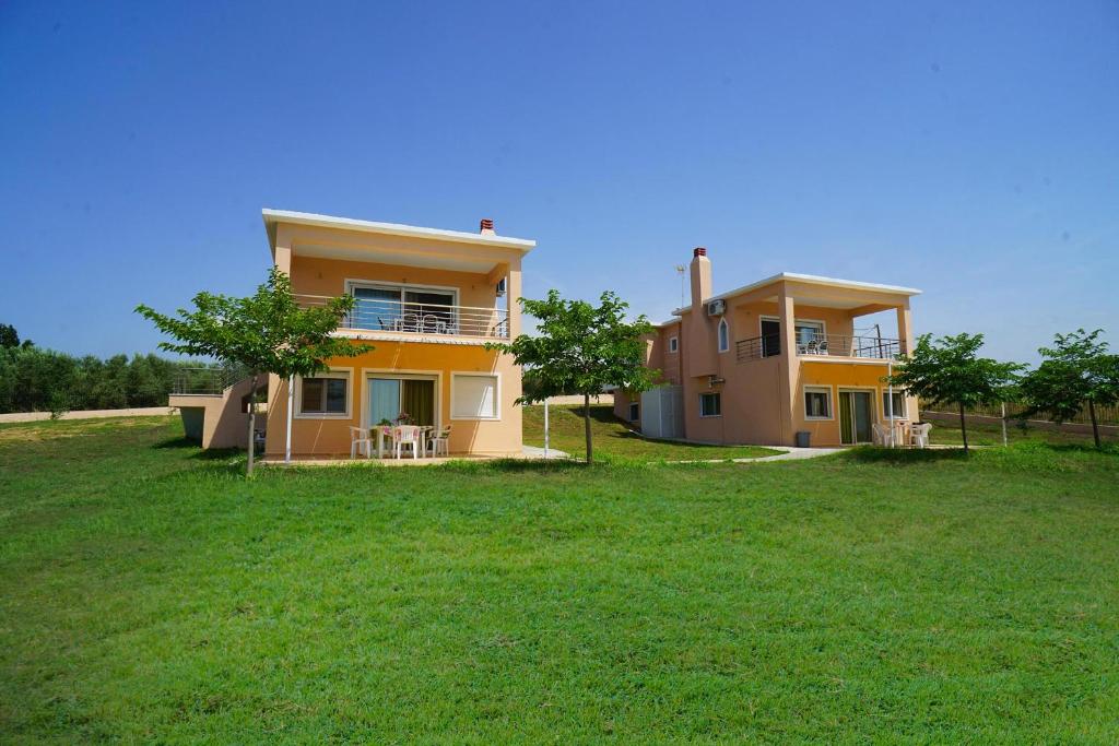 a yellow house with a grassy field in front of it at Makridis Summer Villas in Paralía Avdhíron