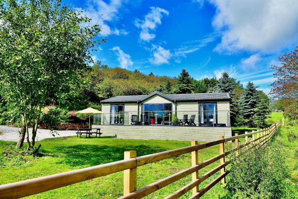 a house with a fence in front of it at Arbennig Luxury Lodges in Mold