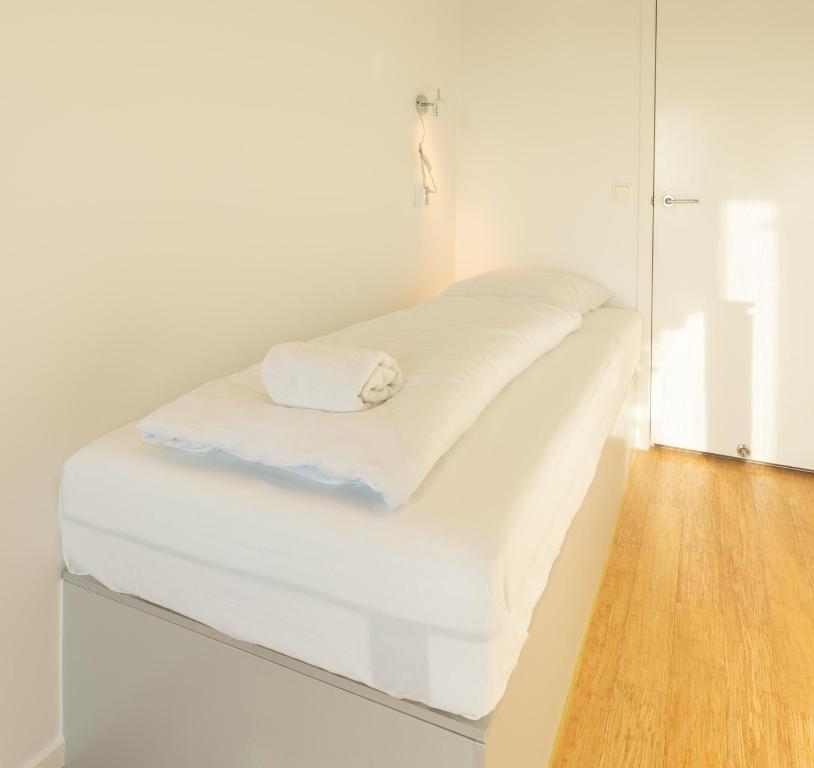 ein weißes Bett in einem Zimmer mit Spiegel in der Unterkunft Stylish Aparthotel in Tórshavn in Tórshavn