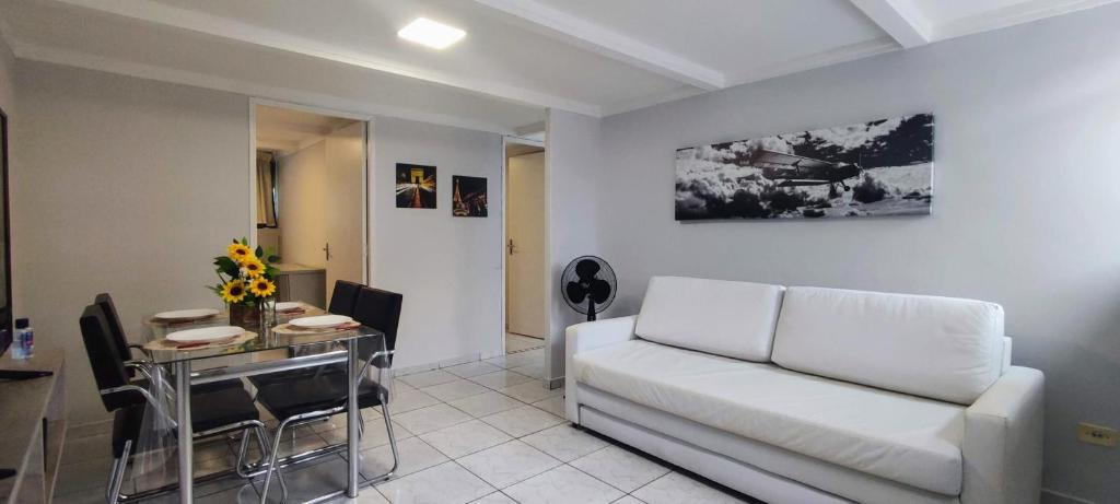 ein Wohnzimmer mit einem weißen Sofa und einem Tisch in der Unterkunft Ao Lado do Aeroporto Com Vaga Coberta e Wifi 300 mb POWER in Guarulhos