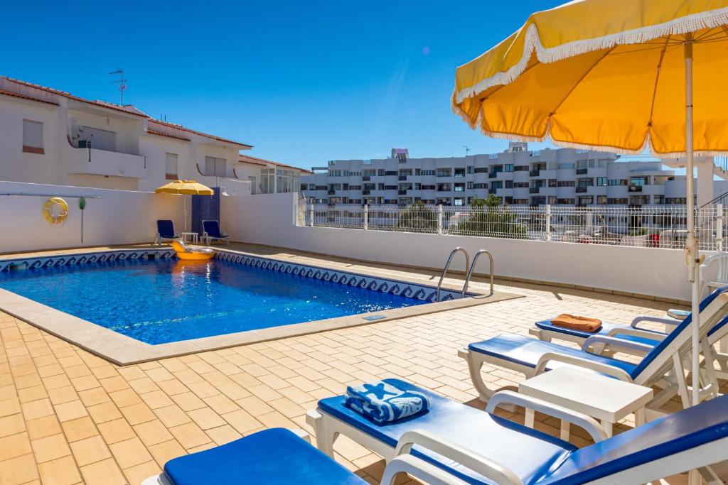 a swimming pool with lounge chairs and an umbrella at Apartamentos Carruna in Albufeira