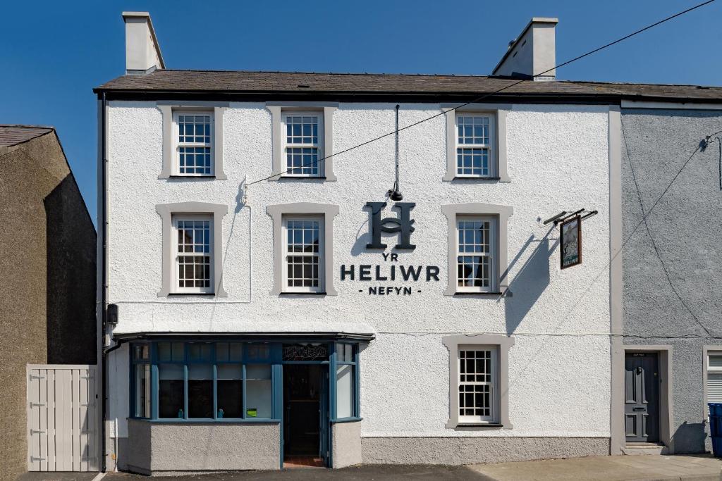 een wit gebouw met een heinemann bord erop bij Tafarn Yr Heliwr in Nefyn
