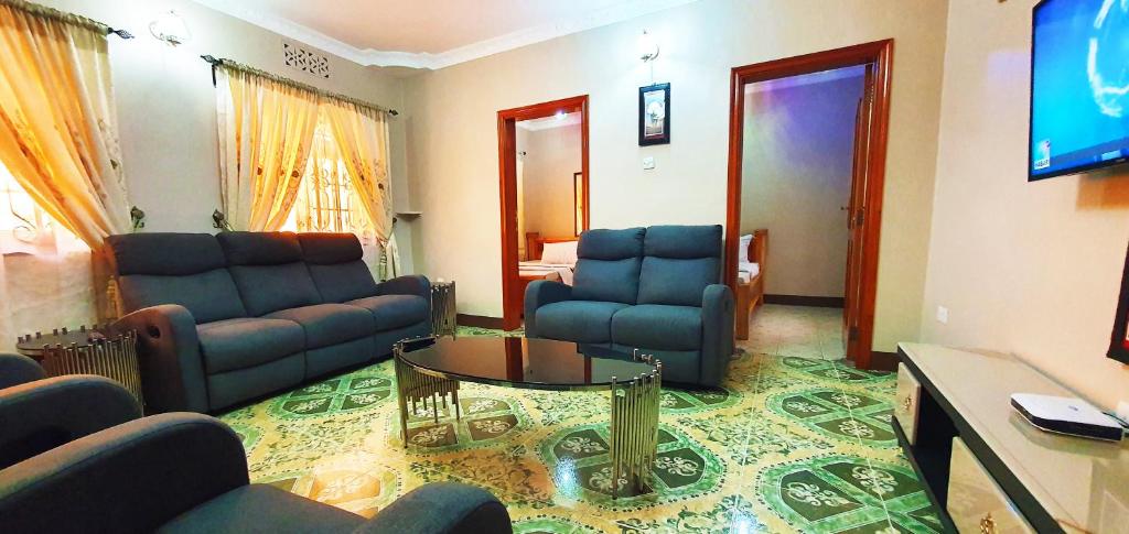a living room with a couch and chairs and a tv at Goodhope 3-Bedroom Vacation Rental in Arusha