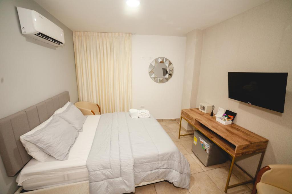 Schlafzimmer mit einem Bett, einem Schreibtisch und einem TV in der Unterkunft Abel Boutique House in Cartagena de Indias