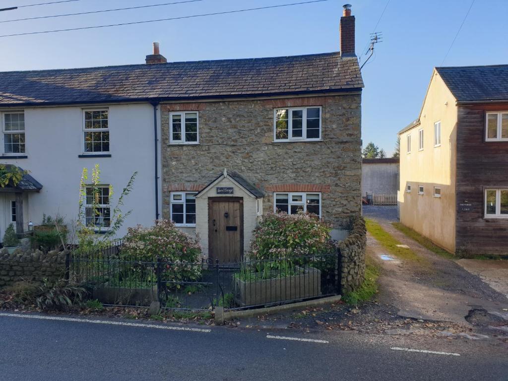 una vieja casa de ladrillo al lado de una calle en Laurel cottage Melplash, en Netherbury