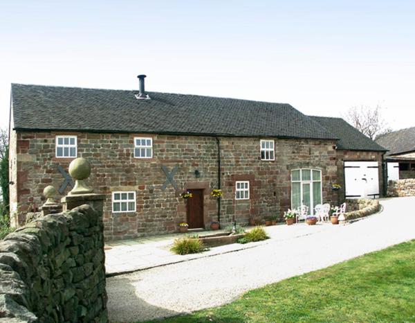 ein Steinhaus mit einem Steinzaun davor in der Unterkunft Meadow Place in Ipstones