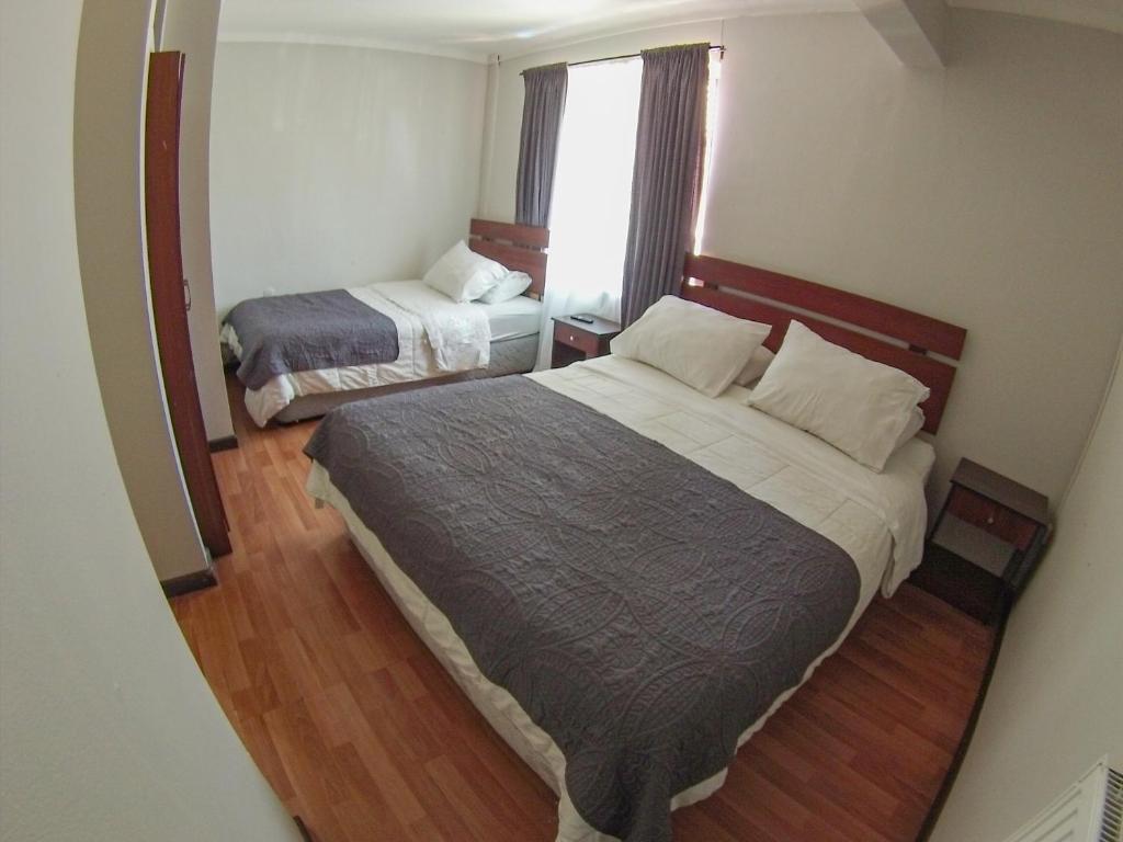 a small bedroom with two beds and a window at Hostal del Rio in Concepción