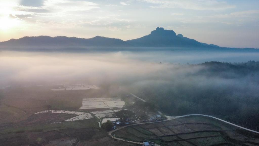 an aerial view of a foggy valley with a mountain at Kaewma farmstay in Ban Khuang Kom