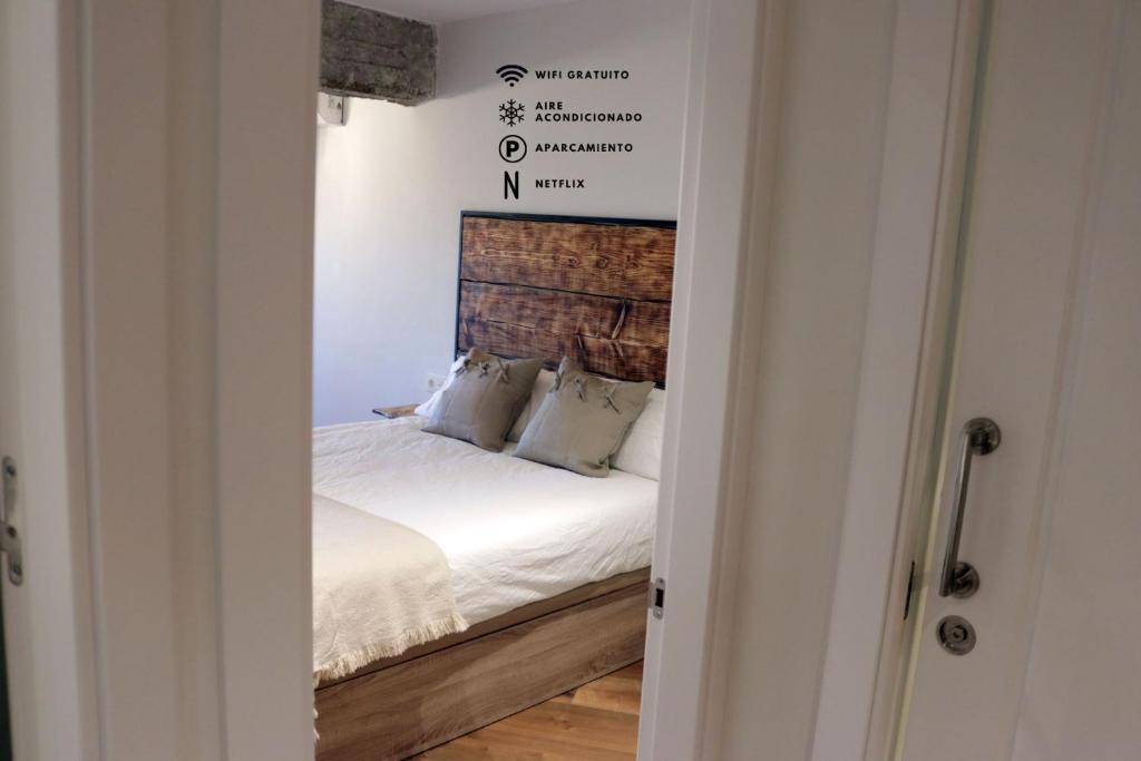 una camera da letto con letto, lenzuola e cuscini bianchi di Ático Industrial Céntrico, Reformado, Air-Acond, Netflix, WiFi a Salamanca